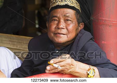 Man attending a funeral ceremony at a rante, the ceremonial site for a Torajan funeral, in Sereale, Toraja Land, South Sulawesi, Indonesia View Large Photo Image Stock Photo - Man attending a funeral ceremony at a rante, the ceremonial site for a Torajan funeral, in Sereale, Toraja Land, South Sulawesi, Indonesia. Fotosearch