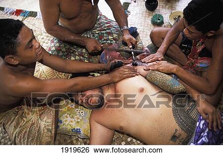 Stock Photograph - Man being tattooed by traditional method, Samoa. Fotosearch