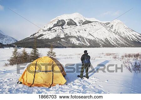 Stock Image - Man Beside Tent In The Snow; Kananaskis, Alberta, Canada. Fotosearch