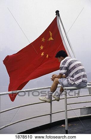 Stock Image - Man By Chinese Flag On Yangzi River Boat. Fotosearch