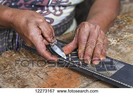 Stock Photo - Man carving a traditional Toraja design on piece of wood, Kete Kesu, Toraja Land, South Sulawesi, Indonesia. Fotosearch