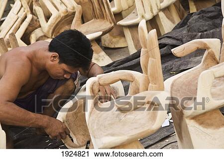 Stock Image - Man Carving Wooden Hand Chairs. Fotosearch