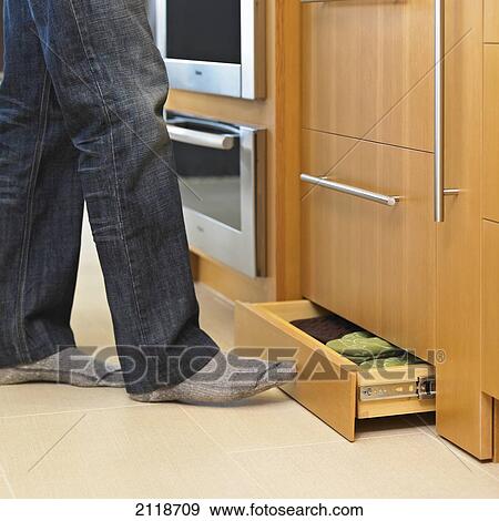 Stock Photo - Man Closing Modern Kitchen Drawer With His Foot; Victoria Vancouver Island British Columbia Canada. Fotosearch