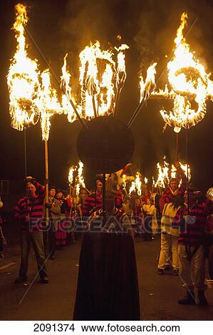 Picture - Man Dressed As Bishop In Front Of People With Burning Banners At Head Of Procession At Barcombe Bonfire Night, Barcombe, East Sussex, Uk. Fotosearch