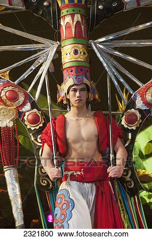 Stock Image - Man dressed in extravagant and colorful costume with tall headpiece; Beijing, China. Fotosearch