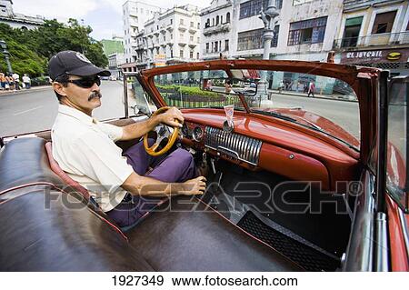 Stock Photo - Man Driving A Chevvy Through Old Town. Fotosearch
