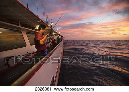 Stock Image - Man fishing at dusk off of boat; Corpus christi texas usa. Fotosearch
