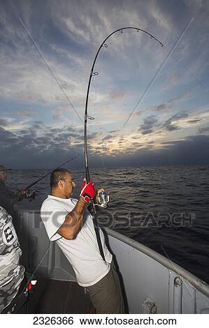 Stock Photograph - Man fishing gets a bite on his line; Corpus christi texas usa. Fotosearch