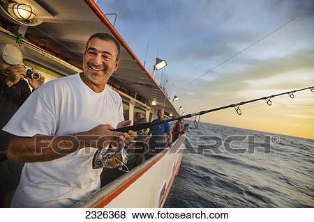 Stock Photo - Man fishing while being photographed; Corpus christi texas usa. Fotosearch