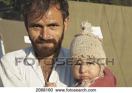 Stock Image - Man Holding A Baby In A Relief Camp After The 8 October 2005 Earthquake, Bagh, Azad Kashmir, Pakistan. Fotosearch