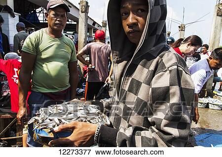 Man holding a bucket of fish at the Paotere fish market, Makassar (Ujung Pandang), South Sulawesi, Indonesia View Large Photo Image Stock Photo - Man holding a bucket of fish at the Paotere fish market, Makassar (Ujung Pandang), South Sulawesi, Indonesia. Fotosearch