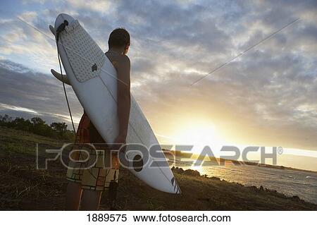 Stock Photography - Man Holding Surfboard At Sunset. Fotosearch