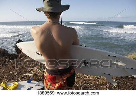Man Holding Surfboard Near Sea, Rear View View Large Photo Image Stock Photo - Man Holding Surfboard Near Sea, Rear View. Fotosearch