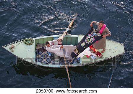 Stock Image - Man In A Boat In The Nile River Selling Textiles, Esna, Qina, Egypt. Fotosearch