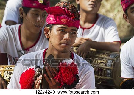 Stock Image - Man in a gamelan ensemble preforming during a Ngaben or Cremation Ceremony, Klungkung, Bali, Indonesia. Fotosearch