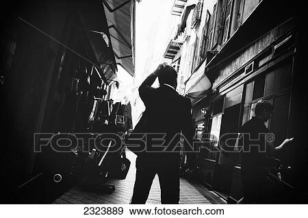 Man in black business suit standing in a narrow alley looking lost; Nice, France View Large Photo Image Stock Photo - Man in black business suit standing in a narrow alley looking lost; Nice, France. Fotosearch