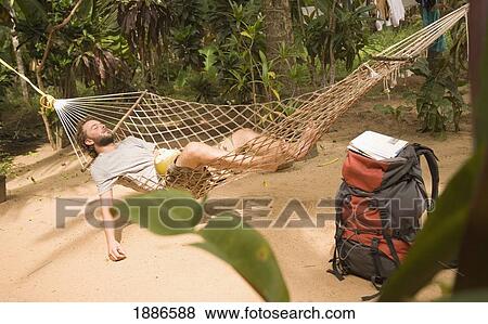 Stock Photo - Man In Hammock With Backpack On Ground. Fotosearch