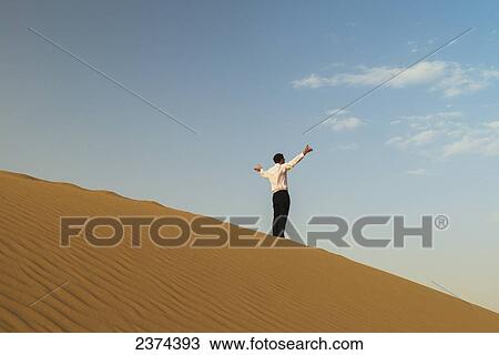 Man in smart clothes waving for attention on top of sand dune; Dubai, United Arab Emirates View Large Photo Image Stock Image - Man in smart clothes waving for attention on top of sand dune; Dubai, United Arab Emirates. Fotosearch