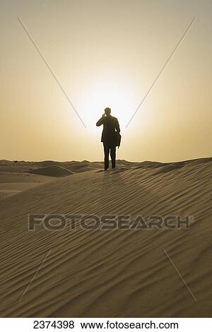 Man in smart suit making phone call on top of sand dune at dusk, Dubai, United Arab Emirates View Large Photo Image Stock Photo - Man in smart suit making phone call on top of sand dune at dusk, Dubai, United Arab Emirates. Fotosearch