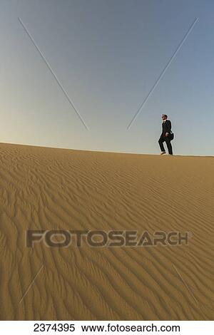 Man in smart suit walking along top of sand dune at dusk; Dubai, United Arab Emirates View Large Photo Image Stock Photography - Man in smart suit walking along top of sand dune at dusk; Dubai, United Arab Emirates. Fotosearch
