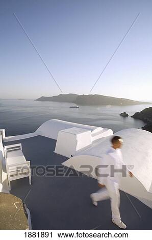 Stock Image - Man In White Walking On Roof Terrace. Fotosearch