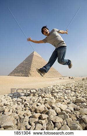 Man Jumping In Air With Pyramid In Background View Large Photo Image Picture - Man Jumping In Air With Pyramid In Background. Fotosearch