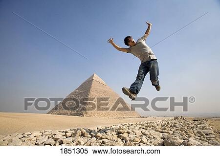 Stock Photography - Man Jumping In Air With Pyramid In Background. Fotosearch