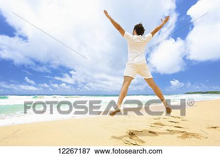 Man jumping in the air on the beach; Kealia, Kauai, Hawaii, United States of America View Large Photo Image Stock Photo - Man jumping in the air on the beach; Kealia, Kauai, Hawaii, United States of America. Fotosearch