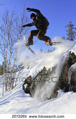 Stock Photography - Man Jumping Off A Rock In Snowshoes, Abitibi-Temiscamingue, Quebec. Fotosearch