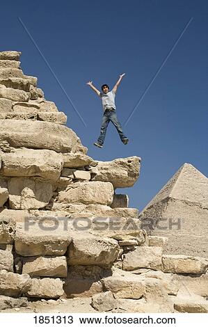 Stock Image - Man Jumping On Part Of A Pyramid In The Desert. Fotosearch