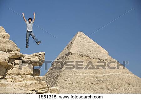 Stock Photography - Man Jumping On Part Of A Pyramid In The Desert; Cairo, Egypt, Africa. Fotosearch
