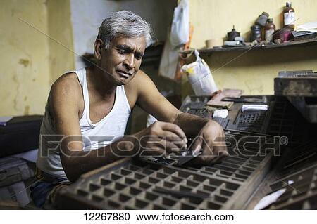 Stock Image - Man laying out type by hand; Kolkata, West Bengal, India. Fotosearch