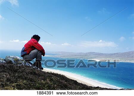 Stock Image - Man Looking Over Rosamol Beach With Taransay In The Distance. Fotosearch