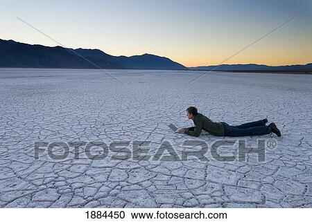 Man Lying Down Using Laptop On The Salt Pans At Dawn View Large Photo Image Stock Image - Man Lying Down Using Laptop On The Salt Pans At Dawn. Fotosearch