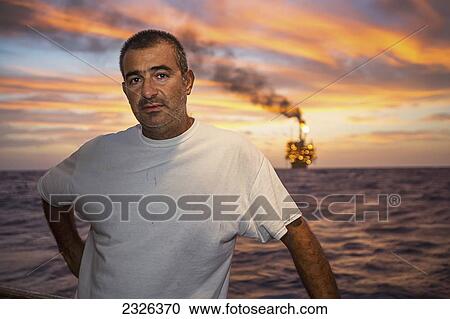 Stock Image - Man on a boat at dusk with perdido oil rig in background; Corpus christi texas usa. Fotosearch