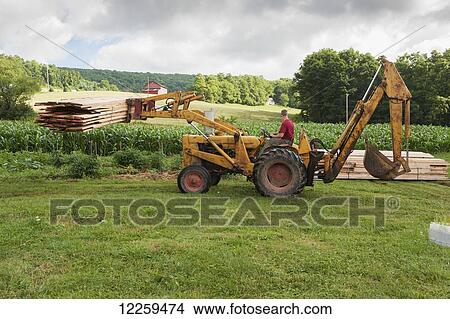 Picture - Man on a tractor moving lumber in Garrett County; Maryland, United States of America. Fotosearch