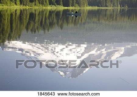 Stock Image - Man On Boat, Mt. Hood Reflects In Trillium Lake; Mt Hood National Forest, Oregon, Usa. Fotosearch
