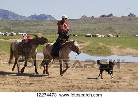 Stock Image - Man on horseback talking on a mobile phone, Elsen Tasarkhai, Arkhangai Province, Mongolia. Fotosearch
