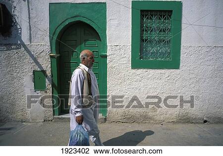 Stock Image - Man On Street, Walking Past Green Door. Fotosearch