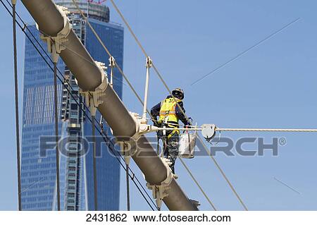 Stock Image - Man painting a suspension cable of the Brooklyn Bridge, New York City, New York, United States. Fotosearch