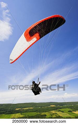 Stock Image - Man Paragliding Over The Fields, Bas-Saint-Laurent Region, Saint-Anaclet, Quebec. Fotosearch