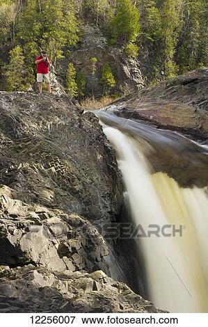 Man photographing a wilderness river waterfall, Ontario, Canada View Large Photo Image Stock Photo - Man photographing a wilderness river waterfall, Ontario, Canada. Fotosearch