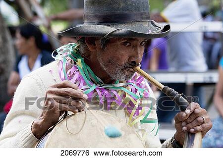 Stock Photograph - Man Playing An Erque, Whilst Drumming On A Caja In The Entrada De Comadritas Parade During The Carnaval Chapaco, Tarija, Bolivia. Fotosearch