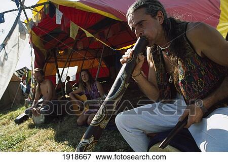 Stock Photo - Man Playing Didgeridoo Outside, Tent. Fotosearch