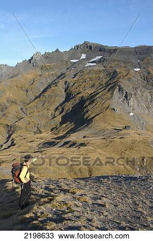 Stock Image - Man Pointing To New Chalet On Dragonfly Peak In Southern Alps; New Zealand. Fotosearch