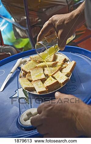 Stock Image - Man Pouring Olive Oil Over Bread. Fotosearch