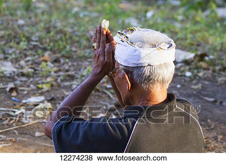 Stock Photo - Man praying during a Ngaben or Cremation Ceremony, Klungkung, Bali, Indonesia. Fotosearch