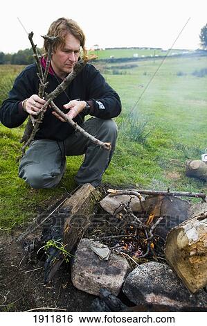 Stock Photograph - Man Preparing Camp Fire In Field, Dartmoor National Park, Postbridge, Yelverton, Devon, Uk. Fotosearch