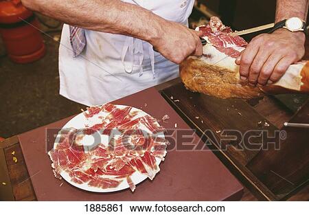 Stock Image - Man Preparing Ham Tapas. Fotosearch