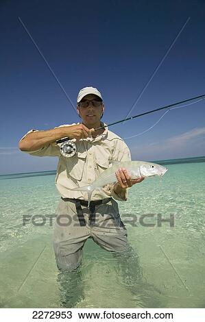 Stock Image - Man Proudly Showing Off A Freshly Caught Fish; Bahamas. Fotosearch